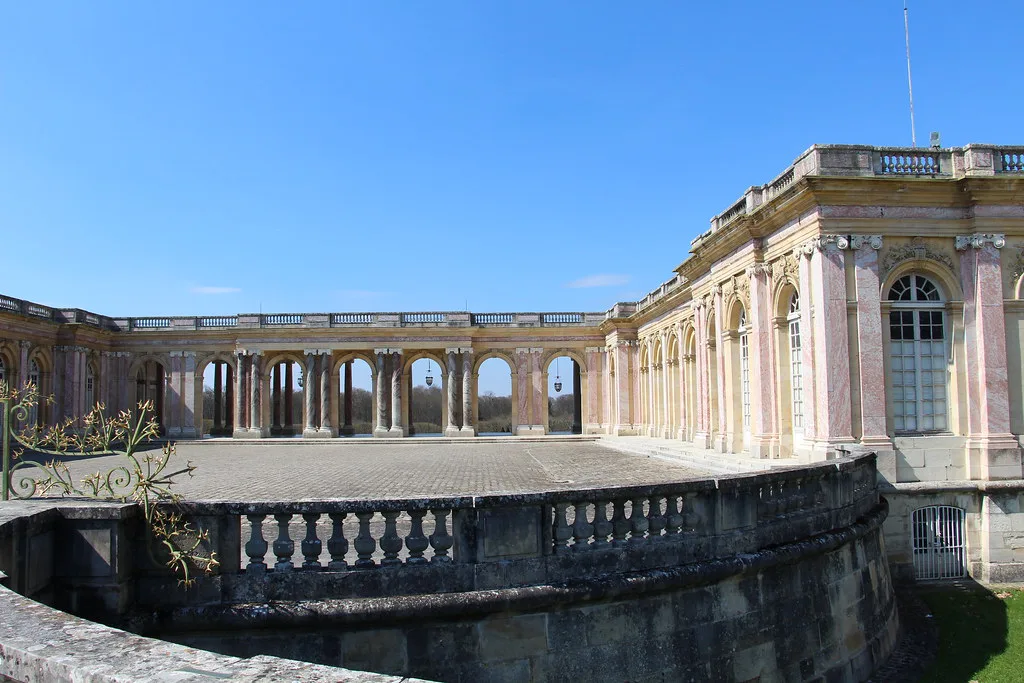 Venue view: the Grand Trianon at Versailles, its pink marble colonnade and gardens. Resized and converted to WebP.