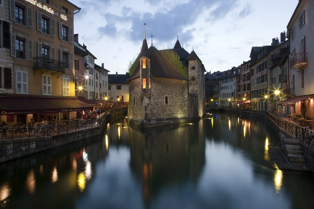 Venue view: The Palais de l'Isle, the 12th-century castle-prison on the Thiou canal in Annecy, reflected at night. Resized and converted to WebP.